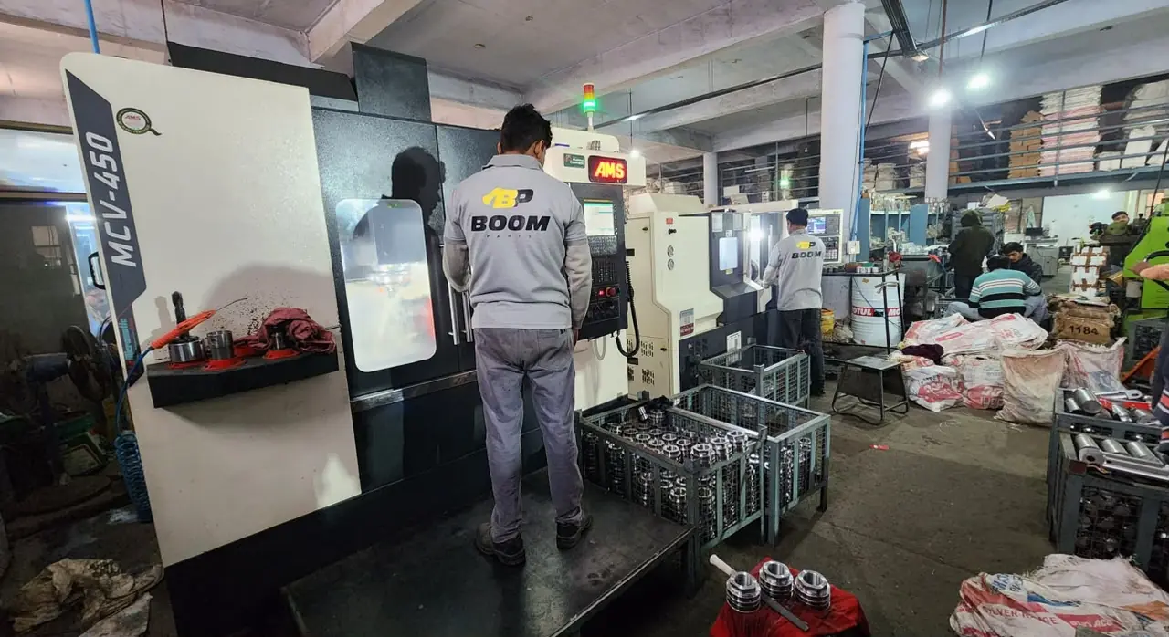 BOOM Parts machinist operating an MCV-450 vertical machining centre, with machined parts in wire bins